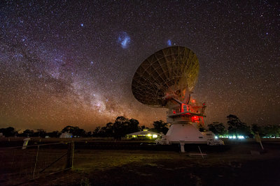 The Large (centre left) and Small (centre right) Magellanic Clouds are seen <br />in the sky above a radio telescope that is part of the Australia Telescope <br />Compact Array at the Paul Wild Observatory in New South Wales, Australia. <br />Image Credit: Mike Salway